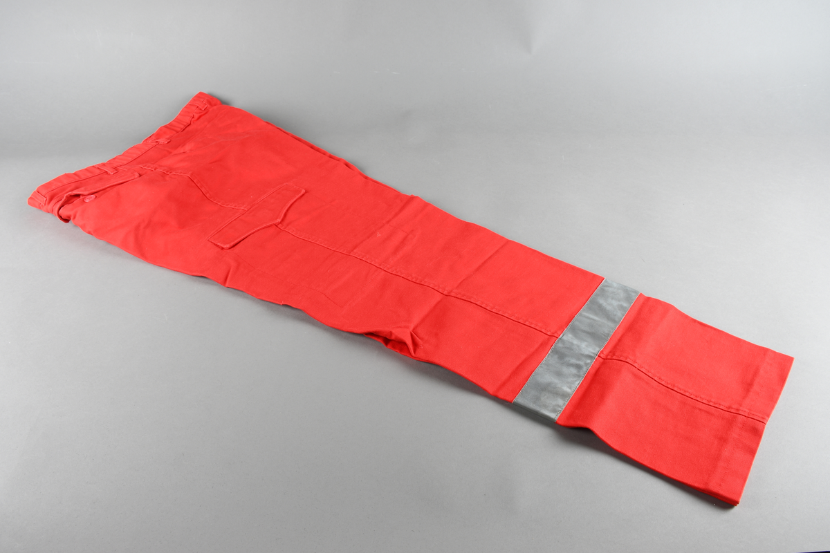 Rød uniformsbukse med glidelås i front og lommer på bein og bakside.