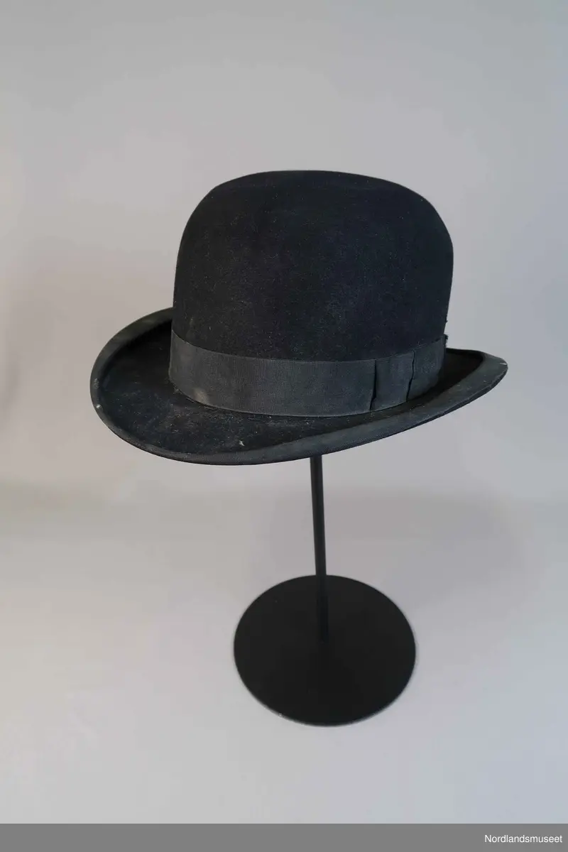 Bowlerhatt, svart filt. Brem kantet med svart silke i ripsbinding. Svettebånd av lys brunt skinn. Lyst silkefor.