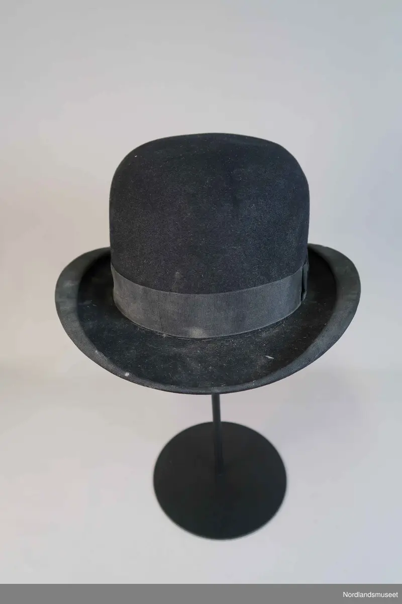 Bowlerhatt, svart filt. Brem kantet med svart silke i ripsbinding. Svettebånd av lys brunt skinn. Lyst silkefor.