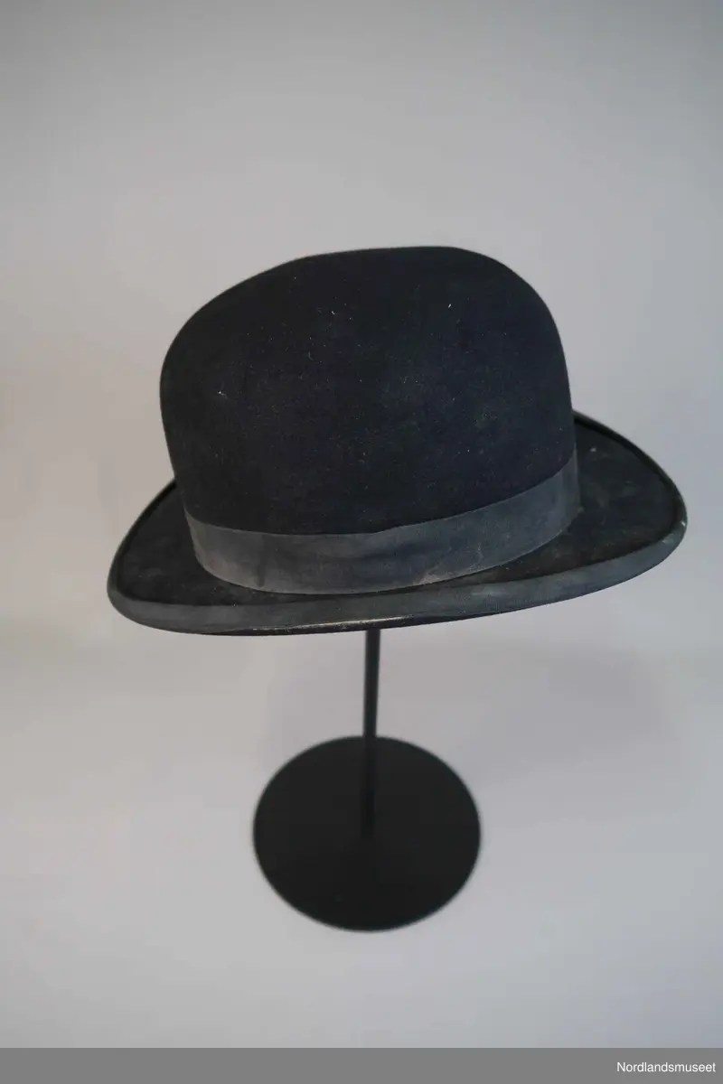 Bowlerhatt, svart filt. Brem kantet med svart silke i ripsbinding. Svettebånd av lys brunt skinn. Lyst silkefor.