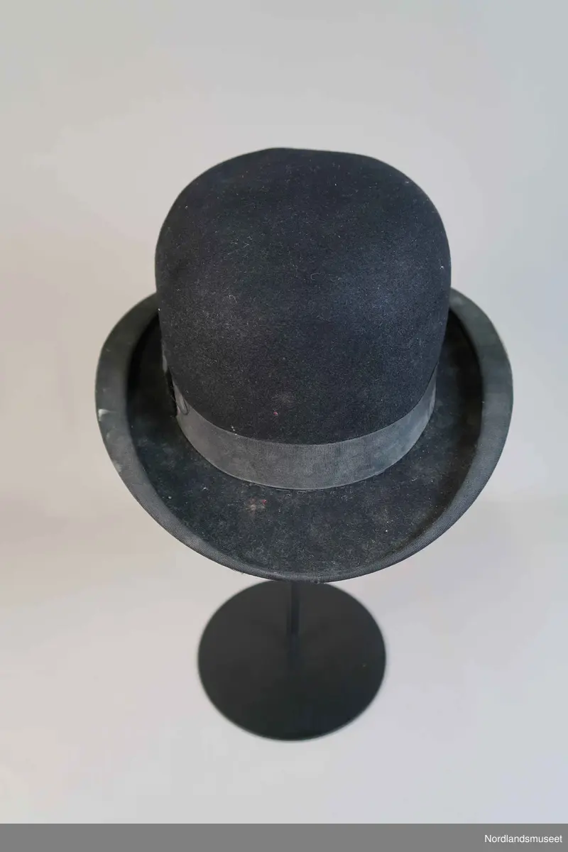 Bowlerhatt, svart filt. Brem kantet med svart silke i ripsbinding. Svettebånd av lys brunt skinn. Lyst silkefor.