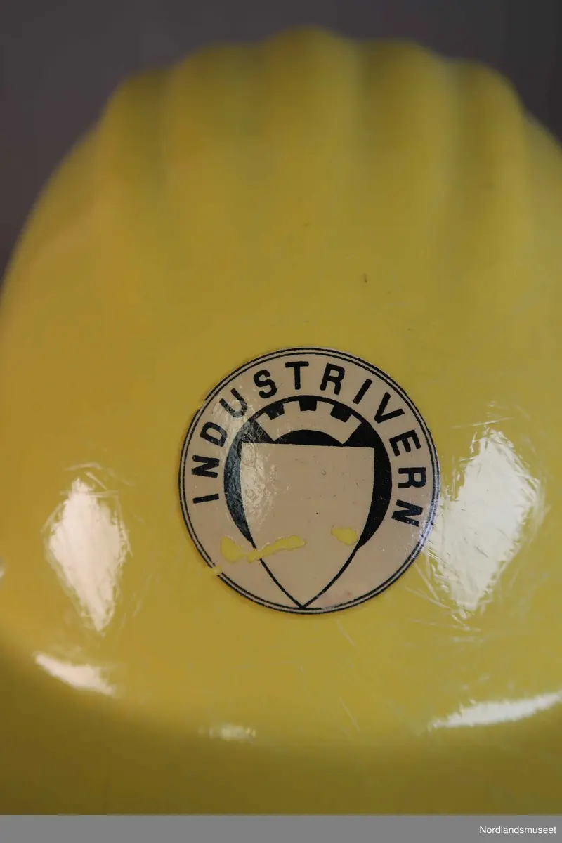 Hjelm i hardplast. Merka med "Industrivern". Feste og reimer i plast på innsiden.