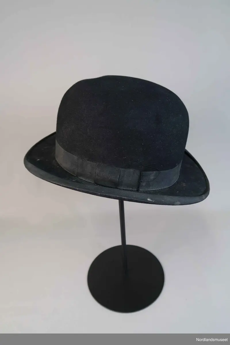 Bowlerhatt, svart filt. Brem kantet med svart silke i ripsbinding. Svettebånd av lys brunt skinn. Lyst silkefor.