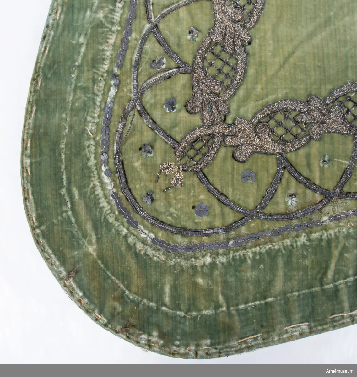 Schabrak av grön silkessammet med metallbroderier och metallpaljetter, kantad med grön skinn samt fodrad med svart bemålad linneduk.