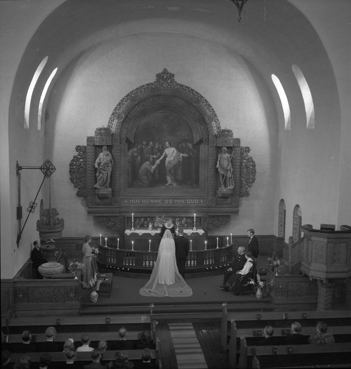 Bryllup i Rjukan kirke for Astri Dahlin og Kjell Moum. Brudeparet står foran alterringen med presten foran seg.