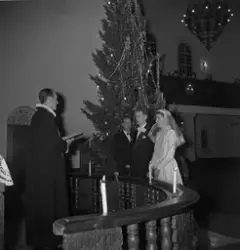 Bryllup i Rjukan kirke for ekteparet Jansen. Brudeparet foran alteret sammen med pastor Selmer. Juletre i bakgrunnen.