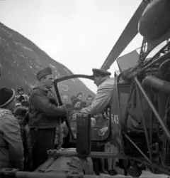 Helikopterlanding ved Tveitoparken. Pilot og copilot står ved helikopter, tilskuere stående rundt.