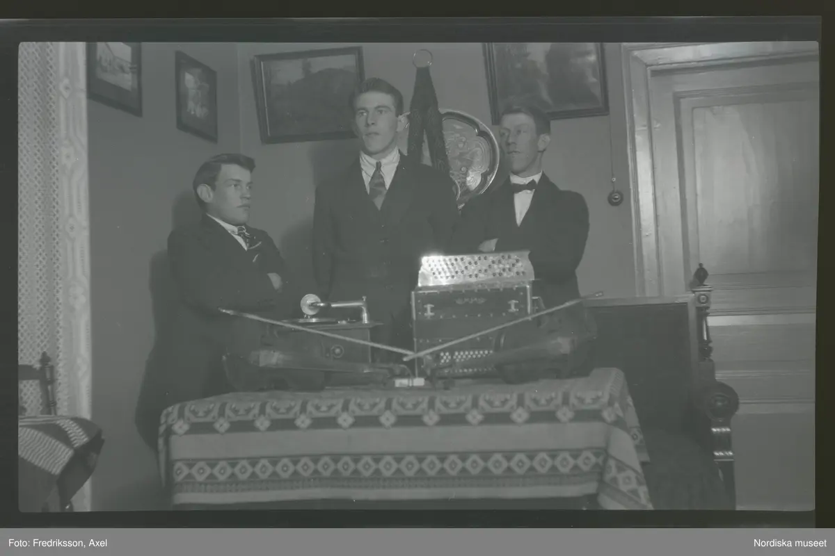 Albin, Gunnar och Johan Karlsson, Glimmersta. På bordet framför dem ligger instrument: dragspel och fioler.