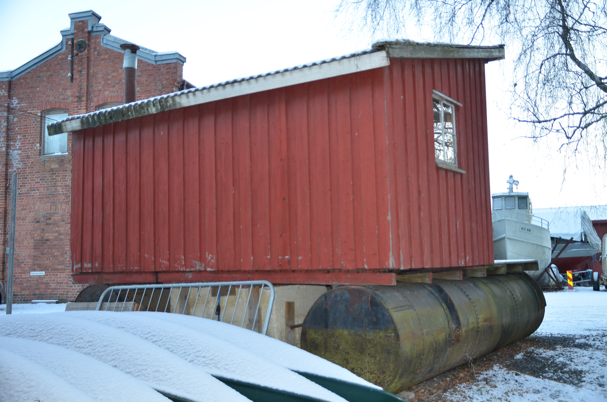 Flytebrygge på to pongtonger med metalltønner. Hvilebrygga dekker havlparten av flytebrygga. Rektangulært grunnplan. Pulttak med bølgeblikk. Dør ved høyre hjørne på langveggen. Kledd med rødmalt over-og underliggere. Ett vindu med fire ruter på hver sidevegg. Lakkert perlestoff panel innvendig på tak og vegger. Hyller i hjørne ved døra og på bakvegg. Jøtulovin, brannmur av eternittplater. Strøm til lys og strømuttak. 
Inspeksjonhull til pongtongene ved hvert brakkehjørne.