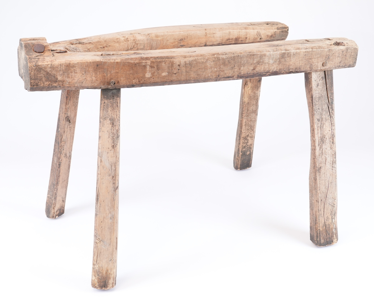 Krakk til bakstebord. Krakken er laga av eit kraftig V-forma trestykke og fire bein som går gjennom hol i dette. Beina er i tillegg festa med ein trekile hamra frå ovanfrå og ein trepinne som går på tvers av elementa. På den smale enden av stativet er det ei djup utskjering slik at bordplata ikkje kan bevege seg under arbeidstida. På den smale enden er det synleg eit stort sprekk som vart reparert med metallnaglar.