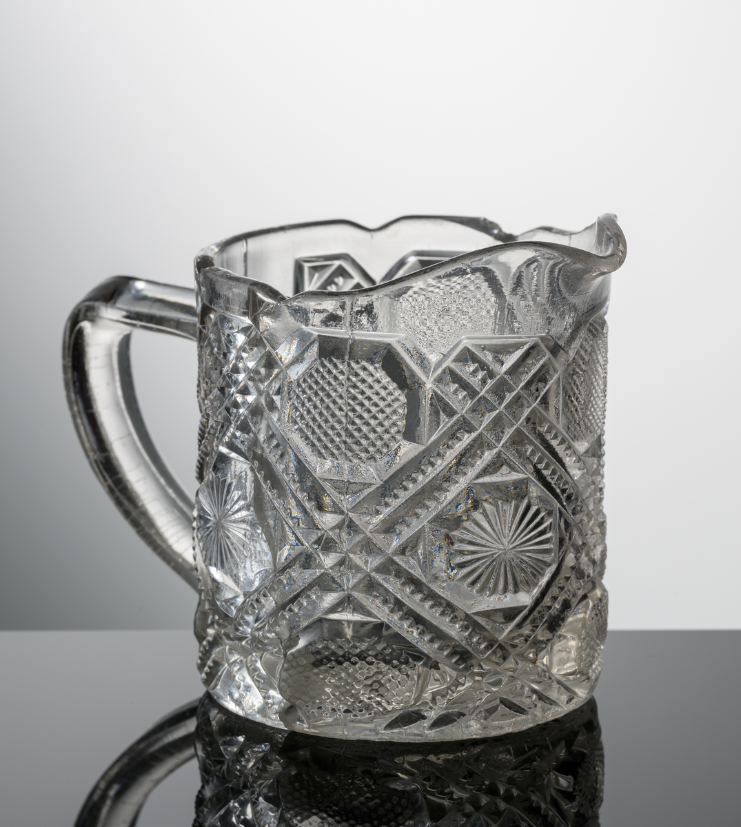 Cylindrisk, övre kanten kantigt vågig, pressat mönster med diagonala ränder, rutor och stjärnor. Under botten en tio-uddig stjärna.