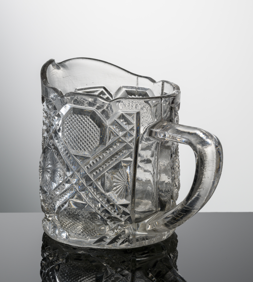 Cylindrisk, övre kanten kantigt vågig, pressat mönster med diagonala ränder, rutor och stjärnor. Under botten en tio-uddig stjärna.