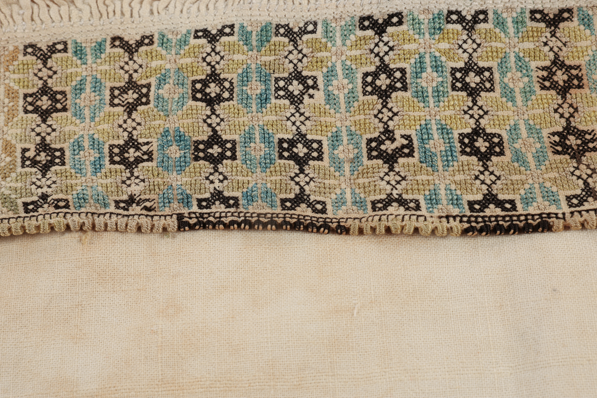 Hvit mannsskjorte med flerfarget broderi som dekor på krave og lengs halssplitt.