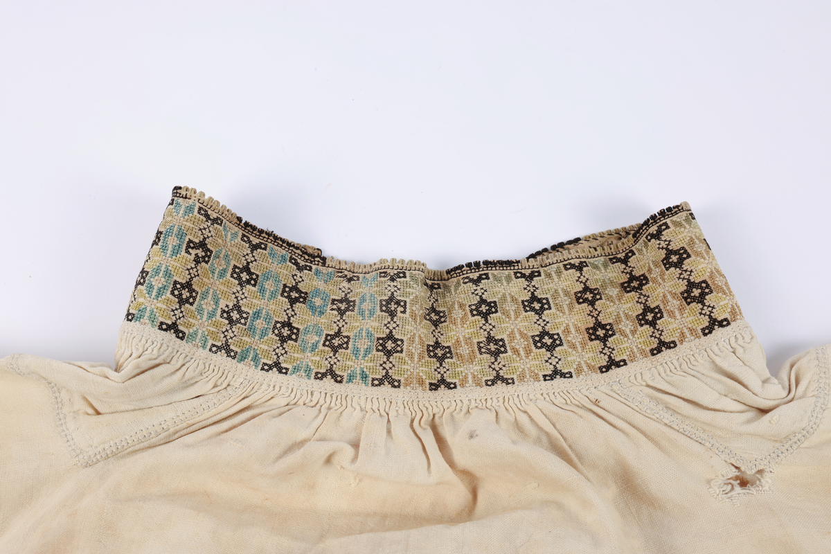 Hvit mannsskjorte med flerfarget broderi som dekor på krave og lengs halssplitt.