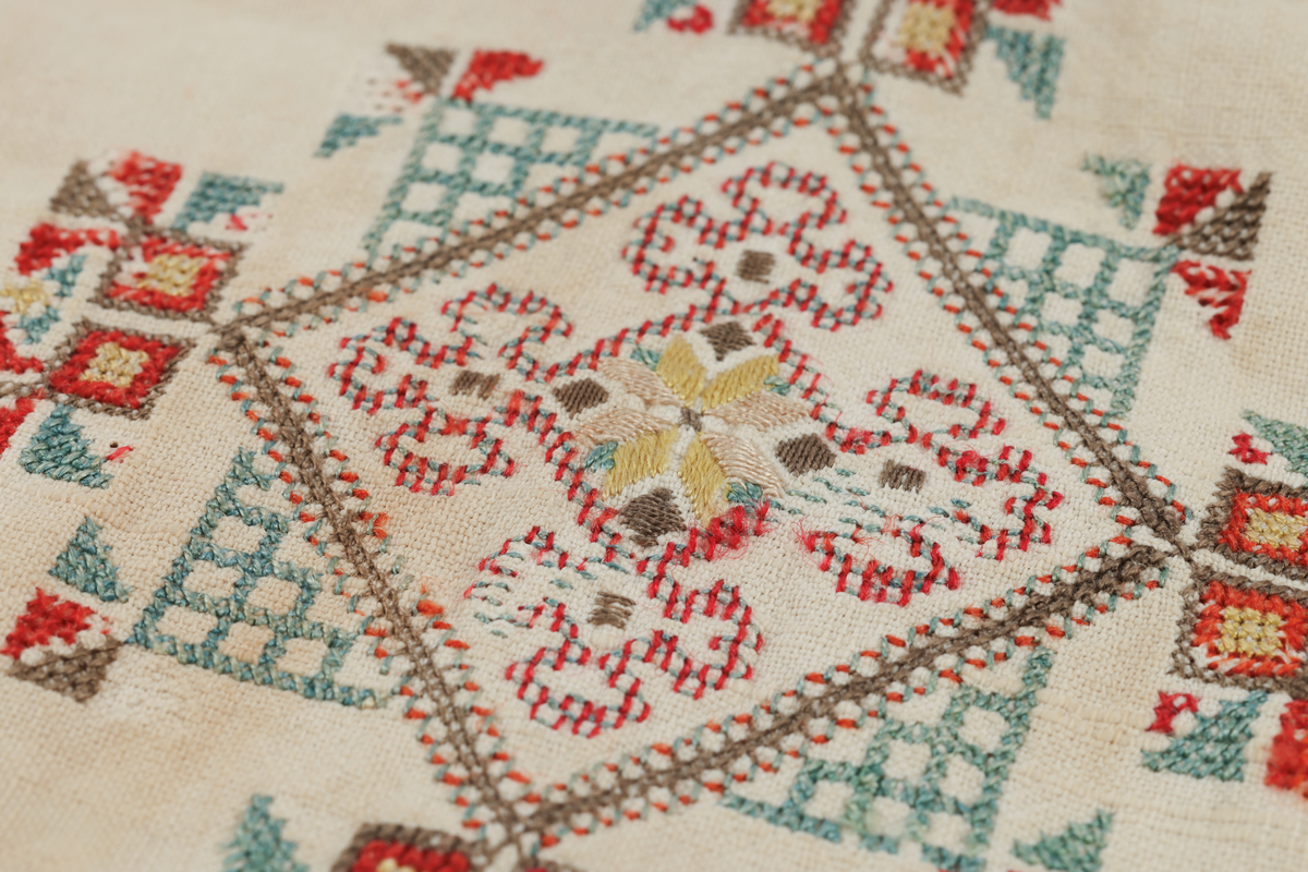 Hvit mannsskjorte med flerfarget broderi som dekor på krave og lengs halssplitt.