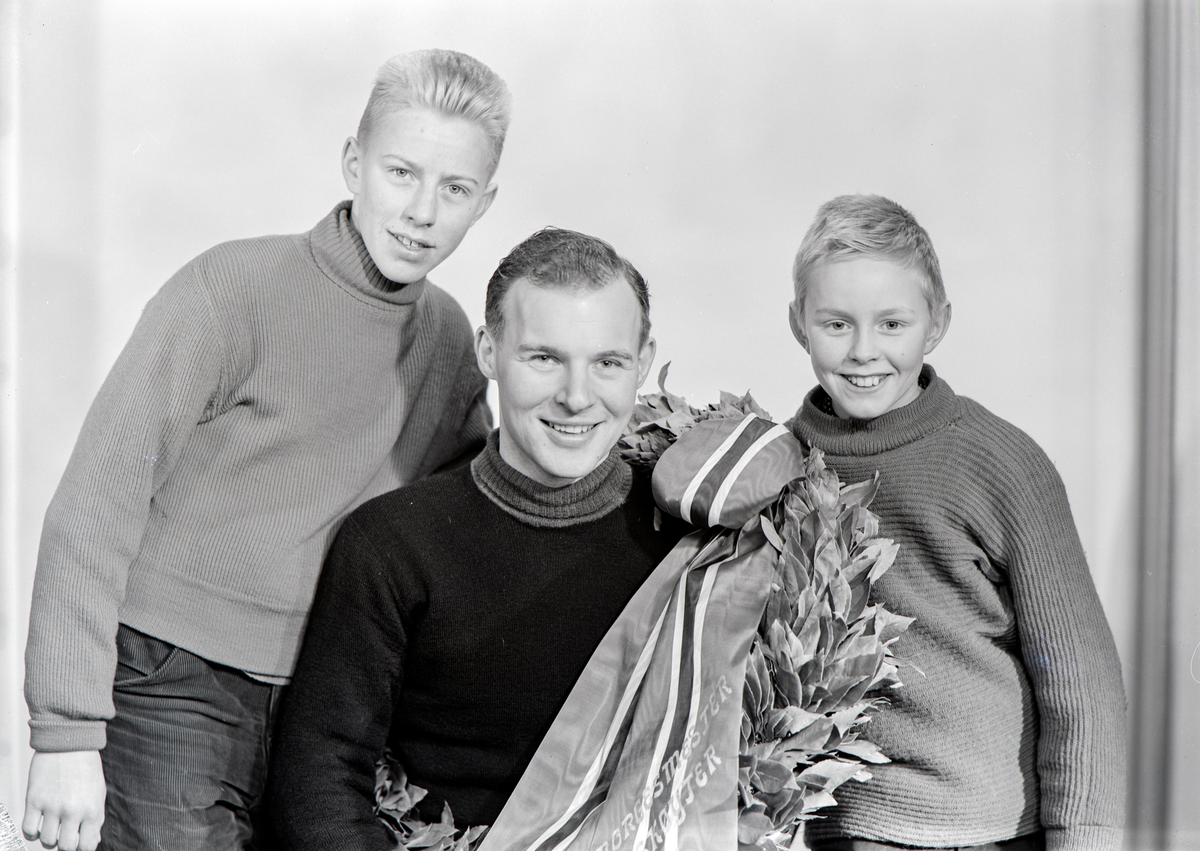 Hamar, Torggata 13, i fotostudioet til fotograf Carl Normann, fotograf Arne T. Knutsen har tatt med sønnene fra venstre Gunnar Knutsen og Tore Knutsen sammen med skøyteløper Knut Johannesen "Kuppern" som er blitt Norgesmester på skøyter på Hamar stadion 20 januar 1963, laurbærkrans,