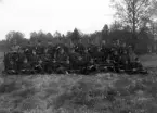 Foto av en pluton meniga i uniform, som samlats för gruppfotografering på en äng.