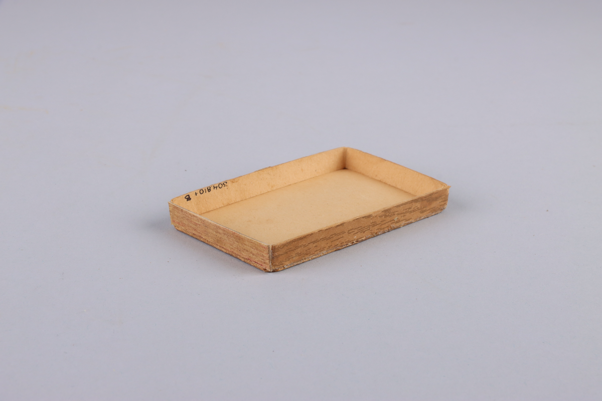 Lock till ask, av hårdpapp som utvändigt klätts i trämönstrat papper. På locket, gul etikett med grönt tryck: "Havanna no 2, no 204 AB Svenska Tobaksmonopolet".