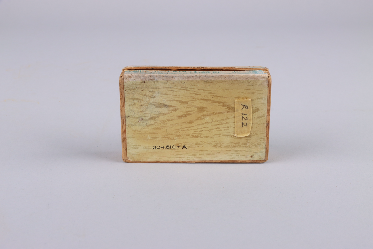 Ask, i två delar, av hårdpapp som utvändigt klätts i trämönstrat papper. På locket, gul etikett med grönt tryck: "Havanna no 2, no 204 AB Svenska Tobaksmonopolet". 