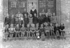 OBS! Svårt anfrätt foto med mögelfläckar m.m.
Foto av en skolklass med lärarinna, som samlats utanför skolans port.