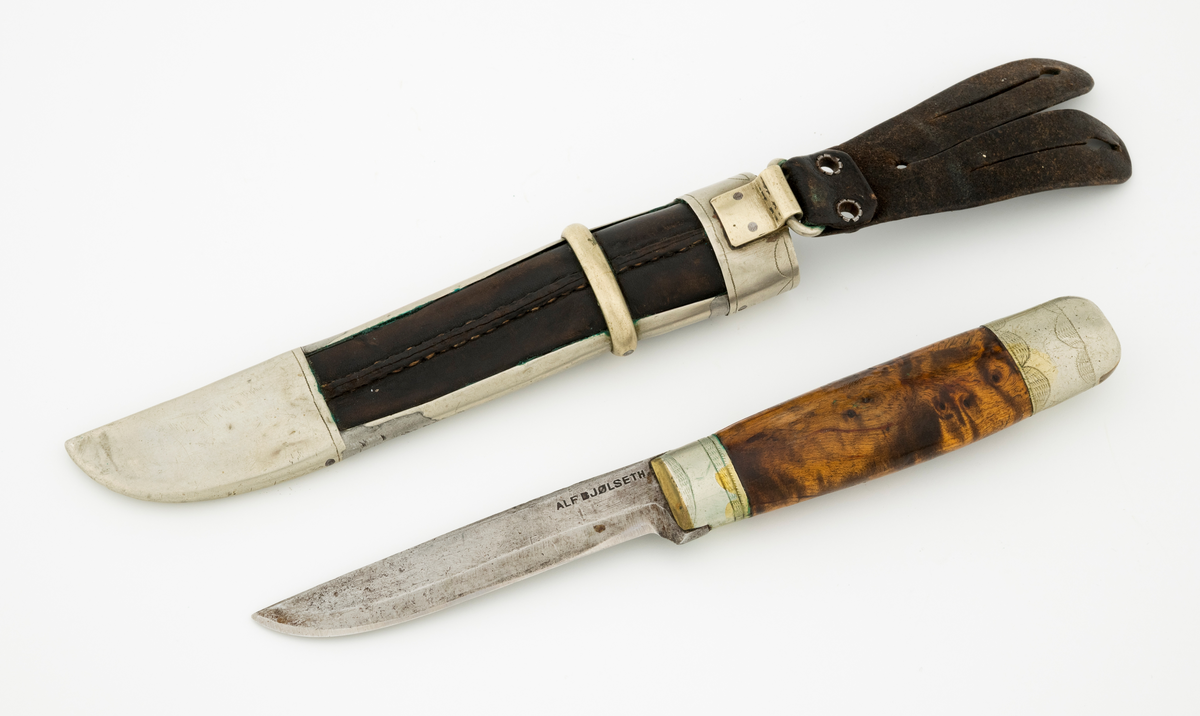 Tollekniv med slire. Knivbladet har stempelet til Alf Bjølseth (1896-1990) fra Malungen i Romedal allmenning, skaftet og slira kan muligens være lagd av Knut Knutsen (1911-1994) fra Ådalsbruk i Løten. Kniven er drøyt 20,4 centimeter lang, målt fra bladspissen til ytterenden av den bakre skaftholken. Bladet utgjør 9,4 centimeter av dette breddemålet. Det har opprinnelig vært 2,2 centimeter bredt ved brystningen, men er nedslipt, slik at gjenstående bredde (bakerst) er cirka 1,7 centimeter. Bladtjukkelsen er 3,7 millimeter bakerst, 2,9 millimeter fremst (umiddelbart bak slipefasene). Bladryggen er en aning konveks i lengderetningen, og den er avfaset mot sidene. Smeden har plassert navnestempelet sitt oppunder bladryggen, bakerst på venstre side. 

Skaftet er lagd av brunbeiset, noe flammet virke, men forsterket med holker, antakelig av nysølv, i begge ender. Treskaftet har ovalt tverrsnitt og er noe konvekst i lengderetningen. På midten er tverrsnittet 2,6 X 1,8 centimeter. Den bakre skaftholken er om lag 2,8 centimeter lang og dekorert med to striper med skravurgraverte sirkelsegmenter. I den ytre enden av holken er det innsatt to kiler av et annet metall, antakelig messing. Den bakre enden av tangen, forlengelsen av knivbladet som er tappet gjennom den sentrale delen av knivskaftet, er stuket mot holken. Den fremre holken på skaftet er om lag 1,7 centimeter lang og har enkelt skravert gravyr. 

Slira er lagd av mørkebrunt lær, innsluttet i ei ramme av nysølv. Lengden fra ytterenden av doppskoen til overenden av munningsholken er 17,1 centimeter. Tverrmålet ved sliremunningen - der vidden er størst - er 3,1 X 3,3 centimeter. Lærhylsteret er sammenføyd med en søm i lengdretningen, plassert på baksida av slira. Det nevnte rammeverket består av doppsko og munningsholk, som er forbundet ved hjelp av to sideskinner. Utenpå sideskinnene er det tredd et snaut 6 millimeter bredt slireband, omtrent der hvor skaftet ender når kniven stikkes ned i slira. Nysølvkomponentene i slireramma ser ut til å være tappet sammen. Doppskoen er asymmetrisk, formet slik at det er tydelig hvilken veg bladet skal vendes i slira. Denne komponenten har inngraverte kantlinjer. Munningsholken har rett overkant, men et oppovervendt innsnitt på den delen av undersida som vender fram når kniven bæres i beltet. Også her er det kantlinjer, og linja langs overkanten er supplert med små buer/sirkelsegmenter på undersida. Læret i «vinduet» mellom doppskoen, sideskinnene og slirebandet er dekorert med ei nedoverpekende pil. På baksida av munningsholken er det montert ei hengsle med en oval ring for opphengsstroppen. I denne er det festet ei tofliket lærhempe med spalteåpninger som gjorde at slira kunne forankres i knapper i bukselinninga til knivbrukeren.