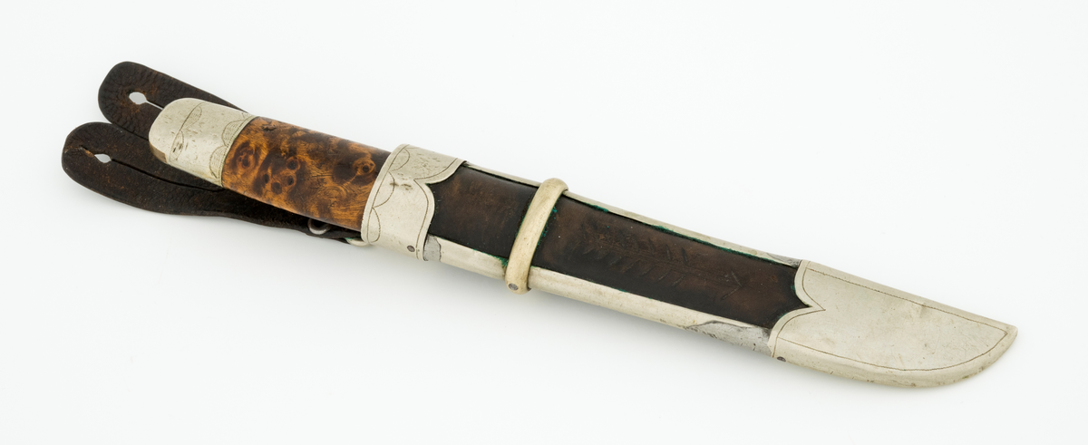 Tollekniv med slire. Knivbladet har stempelet til Alf Bjølseth (1896-1990) fra Malungen i Romedal allmenning, skaftet og slira kan muligens være lagd av Knut Knutsen (1911-1994) fra Ådalsbruk i Løten. Kniven er drøyt 20,4 centimeter lang, målt fra bladspissen til ytterenden av den bakre skaftholken. Bladet utgjør 9,4 centimeter av dette breddemålet. Det har opprinnelig vært 2,2 centimeter bredt ved brystningen, men er nedslipt, slik at gjenstående bredde (bakerst) er cirka 1,7 centimeter. Bladtjukkelsen er 3,7 millimeter bakerst, 2,9 millimeter fremst (umiddelbart bak slipefasene). Bladryggen er en aning konveks i lengderetningen, og den er avfaset mot sidene. Smeden har plassert navnestempelet sitt oppunder bladryggen, bakerst på venstre side. 

Skaftet er lagd av brunbeiset, noe flammet virke, men forsterket med holker, antakelig av nysølv, i begge ender. Treskaftet har ovalt tverrsnitt og er noe konvekst i lengderetningen. På midten er tverrsnittet 2,6 X 1,8 centimeter. Den bakre skaftholken er om lag 2,8 centimeter lang og dekorert med to striper med skravurgraverte sirkelsegmenter. I den ytre enden av holken er det innsatt to kiler av et annet metall, antakelig messing. Den bakre enden av tangen, forlengelsen av knivbladet som er tappet gjennom den sentrale delen av knivskaftet, er stuket mot holken. Den fremre holken på skaftet er om lag 1,7 centimeter lang og har enkelt skravert gravyr. 

Slira er lagd av mørkebrunt lær, innsluttet i ei ramme av nysølv. Lengden fra ytterenden av doppskoen til overenden av munningsholken er 17,1 centimeter. Tverrmålet ved sliremunningen - der vidden er størst - er 3,1 X 3,3 centimeter. Lærhylsteret er sammenføyd med en søm i lengdretningen, plassert på baksida av slira. Det nevnte rammeverket består av doppsko og munningsholk, som er forbundet ved hjelp av to sideskinner. Utenpå sideskinnene er det tredd et snaut 6 millimeter bredt slireband, omtrent der hvor skaftet ender når kniven stikkes ned i slira. Nysølvkomponentene i slireramma ser ut til å være tappet sammen. Doppskoen er asymmetrisk, formet slik at det er tydelig hvilken veg bladet skal vendes i slira. Denne komponenten har inngraverte kantlinjer. Munningsholken har rett overkant, men et oppovervendt innsnitt på den delen av undersida som vender fram når kniven bæres i beltet. Også her er det kantlinjer, og linja langs overkanten er supplert med små buer/sirkelsegmenter på undersida. Læret i «vinduet» mellom doppskoen, sideskinnene og slirebandet er dekorert med ei nedoverpekende pil. På baksida av munningsholken er det montert ei hengsle med en oval ring for opphengsstroppen. I denne er det festet ei tofliket lærhempe med spalteåpninger som gjorde at slira kunne forankres i knapper i bukselinninga til knivbrukeren.