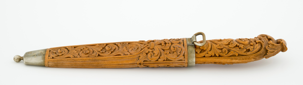 Tollekniv i slire laget av den kjente treskjæreren Ole Olsen Moene (1839-1908) fra Oppdal i Sør-Trøndelag. Kniven har blad som antas å være av jern og stål, mens skaftet og slira er utført i tre, men med beslag av nysølv. 

Kniven er 19,3 centimeter lang. Bladet utgjør 8,9 centimeter av dette lengdemålet. Det er 14,9 millimeter bredt bakerst ved brystningen. Her er tjukkelsen 3,3 millimeter. Bladryggen er noenlunde rettlinjet, men særlig den bakre delen er avfaset mot sidene. Slipefasene er opptil 9 millimeter brede. Bladet er blankpolert. Det har ingen stempler eller andre signaturer som tydeliggjør produsenten, men mye tyder vel på at dette er et «fabrikkblad» - altså en masseprodusert komponent.

Tangen i den bakre enden av skaftet er tappet inn i et snaut 10,5 centimeter langt skaft, lagd av det for nordmenn eksotiske treslaget buksbom (Buxus sempervirens). Dette er en buskvekst som har sin opprinnelige utbredelse i det submeriterrane området. Den fremre skaftenden er forsterket med en 7 millimeter bred skaftholk med glatt overflate. Skaftet er konvekst i formen, og det har, som på knivskaft flest, et ovalt tverrsnitt. Den bakre skaftenden er en aning krum - mot buksida. Skaftet har flatedekkende utskåret dekor, elegant formete akantusranker i cirka 2 millimeter høyt relieff, organisert på to flater, ei på hver av skaftets «bredsider». I den bakre enden er akantusbladene gjennombrudte. 

Slira er et 14,4 centimeter langt hylster, sammensatt av to buete buksbomplater med buete tverrsnitt, holdt ihop av en 5,7 millimeter bred munningsholk i den øvre enden og en 2,6 centimeter høy doppsko med endeknopp i den nedre enden. Bøde doppskoen og munningsholken har glatte overflater. De to buksbomskiene har flatedekkende akantusdekor. På de delene som skal omslutte bladet er akantusrankene innrammet av to ribber som møtes cirka 3,5 centimeter under sliremunningen. Fra disse punktene voksder det rosetter som omgir den nedre (fremre) enden av knivskaftet. På slira er akantusrelieffene om lag 1 millimeter høye. På baksida av munningsholken er detr påloddet ei hempe for et oppheng, som antakelig har vært av lær. Dette opphenget mangler.

Verken kniven eller slira har signaturer som refererer til produsenten.