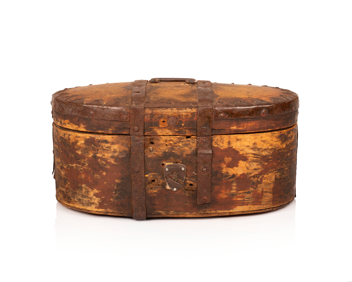 Brun bomme med lås og nøkkel. Den er ovalformet med et svakt hvelvet lokk som er festet med hengsler. Bunnen av bommen er plan. Videre er både bunnen av bommen og toppen av lokket laget av gran, mens sidene er laget av bjørk. 

Lokket og bommens sider er sveipet og består av tynne bjørkelapper, i relativ kraftige dimensjoner, som er brettet sammen for å danne bommens form. Bjørkelappen overlapper hverandre med en god del cm på baksiden og er festet med dobbel nagling. Det er fire nagler i hver av de to rekkene som fester siden sammen. De to rekkene står parallelle overfor hverandre med ca. 5 cm mellomrom. Siden til lokket er festet med en nagle i hver rekke, og i tillegg er det satt inn en nagle nederst på bommen mellom de to rekkene samt en i lokket. 

To smidde jernbånd går fra fremsiden av bommen over lokket og ned på baksiden. På baksiden er det satt inn løkkehengsler i jernbåndene til lokket. Båndene er satt på plass med jernnagler. Rundt toppen av lokket er det et jernbånd som fester lokkets topp og side sammen. Båndet er bøyd over siden, festet med nagler og dekorerte med innovervendte tagger. Midt på bommens lokk er det et håndtak som er festet med nagler. Det er i tillegg jernbånd som går ned på hver side av bommen, disse strekker seg ikke over lokket. 

Bommen har en smidd lås med et hjerteformet nøkkelskilt, og en tilhørende nøkkel. Man kan se rester av brun oljemaling på utsiden av bommen. 