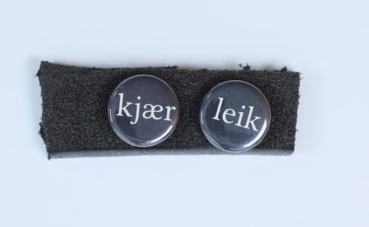 To øyredobbar (utgjer eitt par) med påskrifta "kjær" og "leik"