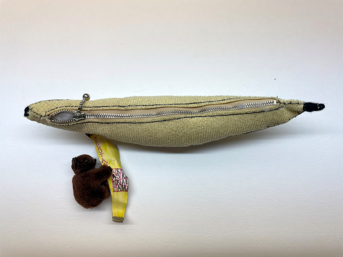 Banan med dragkedja (pennfack?) Bananen är sydd i tyg och ser hemmagjord ut. I bananen finns en brun leksaksbjörn som håller i en utklippt färglagd pappersbanan med svaret på en rebus / ordfläta / korsort ritat. På pappersbananens baksida finns avsändarens namn och adress.

Bananen är adresserad till Klasses frukostklubb, frankerad med ett frimärke (fasttejpade) och poststämplat 1991.