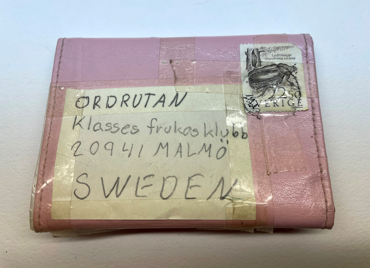 Plånbok i rosafärgat konstläder. Plånboken är adresserad till Ordrutan Klasses frukostklubb.  Frankerad med ett frimärke. 

På insidan står det Föreningsbanken i vit text. I plånboken liggger två skolfotografier på Helene och Lizette som är avsändarna. I sedelfacket finns två papperslappar fasttejpade med deras adresser. I myntfacket svar på ordrutan / rebus. I annat fack ett brev.