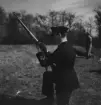 En militär laddar ett gevär vid skjutövning, omkring 1934-1937. Vy snett bakifrån.

Text vid foto: 