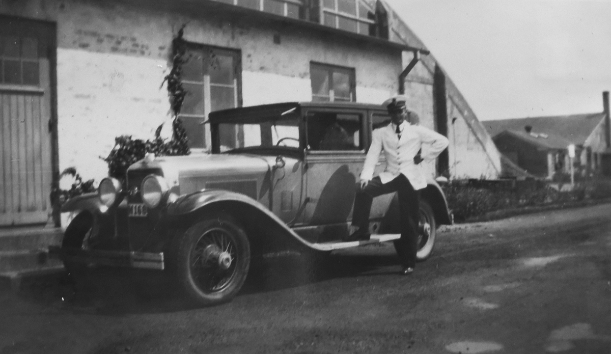 Flygofficeren Nils Olof Sefeldt (Svensson) poserar vid en bil uanför en hangar, iklädd sommaruniform, omkring 1935-1936.

Text vid foto: "Dagofficeren vid sin Sally"