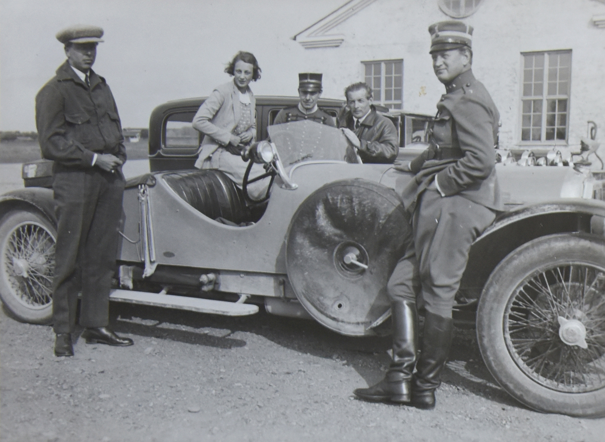 En grupp människor vid en bil framför ett hus, omkring 1935-1937. Två militärer, två civilklädda män och en kvinna.

Text vid foto: "Schinkel vid som Austro Daimler"
