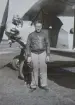 En man med en flygarhuva står framför ett militärt flygplan, omkring 1935-1937.

Text vid foto: 