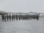 Flygvapenpersonal uppställd på linje framför hangar vid inspektion, 1934.

Text vid foto: 