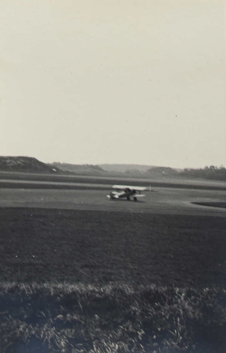 Vy av ett flygfält med ett militärt flygplan, omkring 1934-1937.