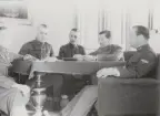 Fem uniformerade män runt ett bord. Foto ur anonym serie från beredskapen i Norrland.