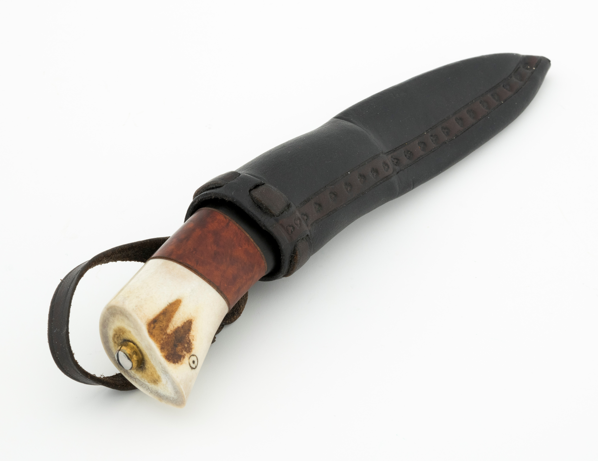 Tollekniv i slire, der knivskaftet og slira er lagd av den danske etnologen, museumslederen og knivmakeren Henrik Vensild, som i mange år besøkte Norsk skogmuseum og det såkalte «knivtorget» under De nordiske jakt- og fiskedager.

Kniven er 20,0 centimeter lang, målt fra bladspissen til og med knappen i ytterenden av skaftet. Bladet er 9,1 centimeter langt og snaut 2,3 centimeter bredt ved brystningen (overgangen til skaftet). Her er bladtjukkelsen om lag 3,7 millimeter, men den avtar noe framover mot knivspissen. Umiddelbart bak slipefasen der er tjukkelsen snaut 2,6 millimeter. Overflata på bladet har den noe rue overflata den fikk av hammeren på ambolten intakt, men disse flatene er polerte. Bakerst på høyre side finner vi et stempel, «Steen N.», som er stempelet til den danskfødte smeden Steen Nielsen, som lenge har bodd i Kristiansand. Bladryggen er planslipt, men er samtidig noe avrundet i den fremre enden. Slipefasene er opptil 6,5 millimeter brede.

Skaftet er nesten 10,5 centimeter langt. Det buer noe nedover (mot skaftbuken) i den bakre enden og har, som knivblader flest, et ovalt tverrsnitt. Sett i lengderetningen er den midtre delen av denne knivdelen noe konveks. Skaftet er sammensatt av flere komponenter. Fremst, mot bladet, er det en del av horn, antakelig reinsdyrgevir. Den enden som vender mot bladet er rett (butt), den andre enden er skrått avskåret. Mot denne flata er det lagt ei lærforing, deretter ei sølvplate og så nok ei lærforing. Deretter følger et stykke brunt, mønstret tre, en svart ring av et ibenholtliknende materiale. og nok et stykke av det brune, mønstrete treet. Ytterenden er skråskåret. På den skrå endeflata er det lagt nok ei lærforing, denne gangen uten noe metallinnlegg, mot endetappen, som er av reisdyrhorn. På denne komponenten er det to små ringer med et punkt i sentrum, en slags signatur for Henrik Vensild. Tangen fra knivbladet er ført gjennom hele skaftet. Den bakre enden av denne jernteinen er klinket mot noe som later til å være en messingring.

Slira er sydd av mørkebrunt lær. Den er cirka 16,9 centimeter lang (uten beltestropp) og 3,4 centimeter bred (målt på midten). Slireformen er symmetrisk, når man ser bort fra at overkanten er skrått avskåret. Den nedre delen, som skal omslutte bladet, er nokså flattrykt, mens den øvre delen, som skal omslutte nedre del av skaftet, er mer rundoval. Sliras forside er dekorert med to parallelle linjer i lengderetningen med innstemplete små treflikete blader med noenlunde regelmessig innbyrdes avstand. Dette dekorelementet er, åpenart med hensikt, plassert på en måte som bryter litt med den nevnte symmetrien. Like under sliremunningen er det skåret små spalter i slirelæret. Her er det inntredd ei cirka 9 millimeter bredt lærreim, som også er tredd gjennom ei spalte i et «øre» på den øvre delen av sliresømmen. Endene på den nevnte lærreima er knyttet sammen slik at den danner ei løkke som kan tres inn på et belte. Henrik Vensild har stemplet inn initialene sine og produksjonsåret - 2005 - på baksida av sliras overdel.