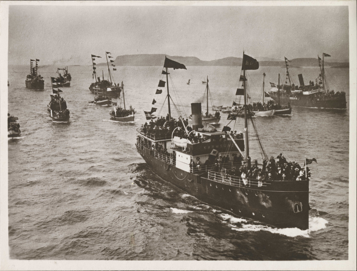 KRISTIANIAFJORD på vei inn til Bergen havn. DS KARMSUND og en rekke småbåter følger dampskipet.
