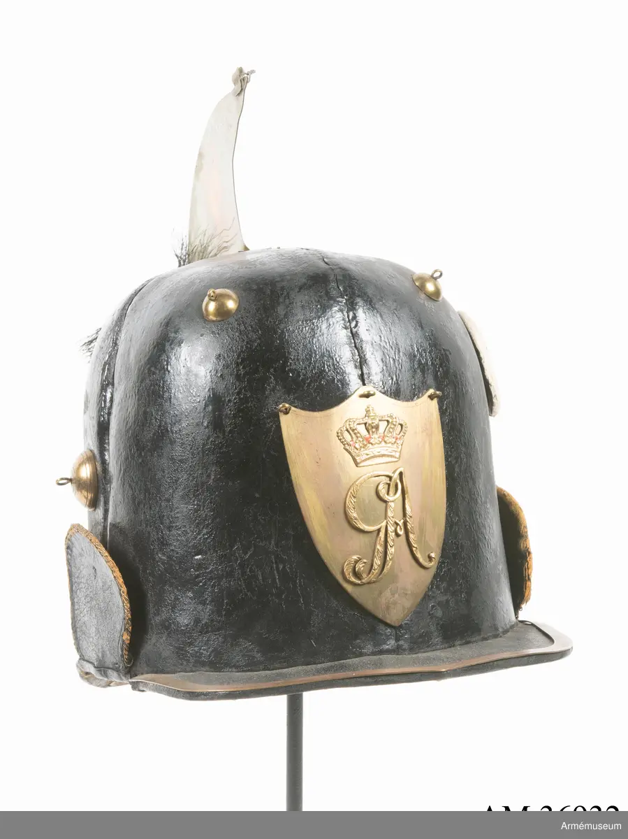 Kask med vapenplåt för manskap vid Västgöta (linje-)dragonregemente, troligen 1805-1807. Inrättad för plym som fattas. Vapenplåt med Gustaf IV Adolfs namnchiffer.