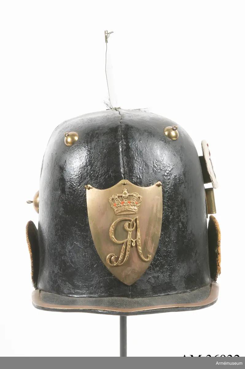 Kask med vapenplåt för manskap vid Västgöta (linje-)dragonregemente, troligen 1805-1807. Inrättad för plym som fattas. Vapenplåt med Gustaf IV Adolfs namnchiffer.