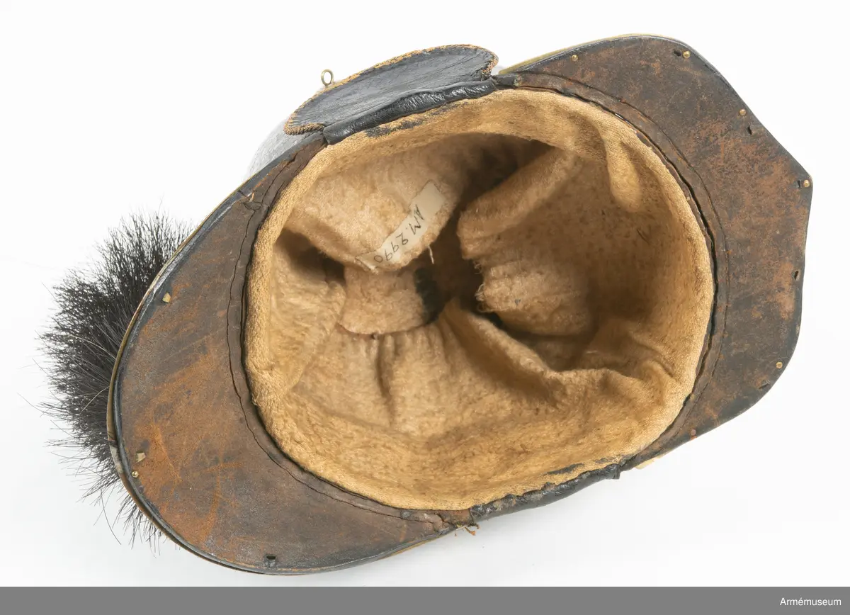 Kask med vapenplåt för manskap vid Västgöta (linje-)dragonregemente, troligen 1805-1807. Inrättad för plym som fattas. Vapenplåt med Gustaf IV Adolfs namnchiffer.