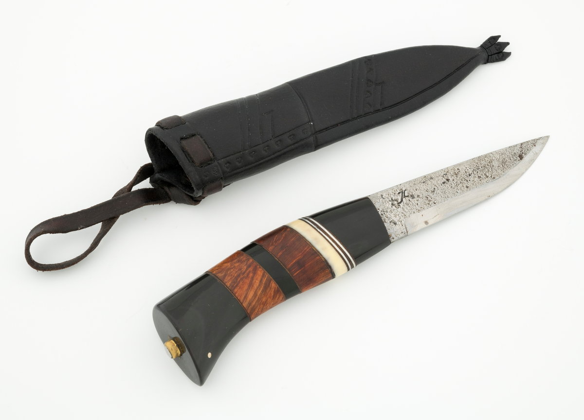 Tollekniv i slire, der knivskaftet og slira er lagd av den danske etnologen, museumslederen og knivmakeren Henrik Vensild, som i mange år besøkte Norsk skogmuseum og det såkalte «knivtorget» under De nordiske jakt- og fiskedager.

Kniven er 20,3 centimeter lang, målt fra bladspissen til og med knappen i ytterenden av skaftet. Bladet er 9,5 centimeter langt og 2,3 centimeter bredt ved brystningen (overgangen til skaftet). Her er bladtjukkelsen om lag 3,7 millimeter, men den avtar noe framover mot knivspissen. Umiddelbart bak slipefasen der er tjukkelsen 1,8 millimeter. Overflata på bladet har den noe rue overflata den fikk av hammeren på ambolten intakt, men disse flatene er polerte. Bakerst på høyre side finner vi et stempel, «JL», som er stempelet til smeden. Bladryggen er planslipt og en aning konveks i lengderetningen. Slipefasene er opptil 7,5 millimeter brede.

Skaftet er nesten 10,5 centimeter langt. Det buer noe nedover (mot skaftbuken) i den bakre enden og har, som knivblader flest, et ovalt tverrsnitt. Sett i lengderetningen er den fremre halvdelen av denne knivdelen noe konveks. Skaftet er sammensatt av flere komponenter. Fremst, mot bladet, er det en del av et svart, ibenholtliknende materiale. Den enden som vender mot bladet er rett (butt), den andre enden er skrått avskåret. Mot denne flata er det lagt ei lærforing, deretter ei sølvplate og så nok ei lærforing. Deretter følger ytterligere ei lærforing, ei sølvplate og nok ei lærforing. Så følger ei lys, cirka 6 millimeter bred hornskive. Så følger en bit i brunt tre, muligens briarrot, nok en bit av det svarte materialet og nok en bit av det brune treet. Ytterenden er også av det samme svarte materialet som vi finner i den fremre skaftenden. I denne komponenten er det inntappet to små sølvstaver, antakelig som en slags signatur for Henrik Vensild. Tangen fra knivbladet er ført gjennom hele skaftet. Den bakre enden av denne jernteinen er klinket mot noe som later til å være en messingring.

Slira er sydd av mørkebrunt lær. Den er cirka 18,4 centimeter lang (uten beltestropp) og 3,3 centimeter bred (målt på midten). Slireformen er symmetrisk, når man ser bort fra at overkanten er skrått avskåret. Den nedre delen, som skal omslutte bladet, er nokså flattrykt, mens den øvre delen, som skal omslutte nedre del av skaftet, er mer rundoval. Sliras forside er dekorert med linjer i lengderetningen og noe skrått på tvers. Mellom parallelle linjer der det innstemplet små treflikete blader med noenlunde regelmessig innbyrdes avstand. Dekorelementene er, åpenbart med hensikt, plassert på en måte som bryter litt med den nevnte symmetrien i sliras ytre form. Like under sliremunningen er det skåret små spalter i slirelæret. Her er det inntredd ei cirka 8,5 millimeter bredt lærreim, som også er tredd gjennom ei spalte i et «øre» på den øvre delen av sliresømmen. Endene på den nevnte lærreima er knyttet sammen slik at den danner ei løkke som kan tres inn på et belte. I den nedre enden av slira er det et trefliket dekorelement. Henrik Vensild har stemplet inn initialene sine og produksjonsåret - 2005 - på baksida av sliras overdel.