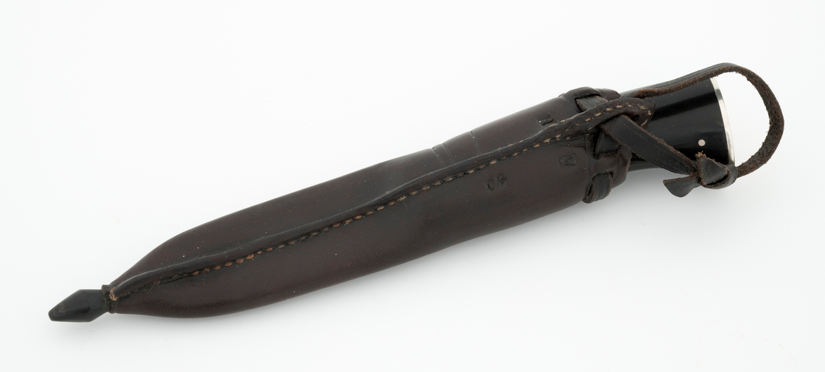 Tollekniv i slire, der knivskaftet og slira er lagd av den danske etnologen, museumslederen og knivmakeren Henrik Vensild, som i mange år besøkte Norsk skogmuseum og det såkalte «knivtorget» under De nordiske jakt- og fiskedager.

Kniven er 20,0 centimeter lang, målt fra bladspissen til og med knappen i ytterenden av skaftet. Bladet, som er damasksmidd, er 8,8 centimeter langt og 2,5 centimeter bredt ved brystningen (overgangen til skaftet). Her er bladtjukkelsen om lag 3,7 millimeter, men den avtar noe framover mot knivspissen. Umiddelbart bak slipefasen der er tjukkelsen 2,6 millimeter. Overflata på bladet var glattslipt og polert. Bakerst på høyre side finner vi et stempel, «B», som er stempelet til smeden. Bladryggen er rettslipt i lengderetningen og noe avrundet i tverrsnitt. Den fremre enden skrår noe nedover. Slipefasene er opptil 7,5 millimeter brede.

Skaftet er nesten 11,2 centimeter langt. Det buer noe nedover (mot skaftbuken) i den bakre enden og har, som knivblader flest, et ovalt tverrsnitt. Sett i lengderetningen er den fremre halvdelen av denne knivdelen noe konveks. Skaftet er sammensatt av flere komponenter. Fremst, mot bladet, er det ei 2,5 millimeter bred metallskive, muligens av nysølv. Deretter følger en bit av gulkvitt hornmateriale, ei nysølvskive, så en noe bredere bit av et svart, ibenholtliknende materiale. Så følger ei skive av dset kvite hornmaterialet, og deretter en stor bit av det svarte ibenholtliknende materialet. På den bakre delen er det inntappet to sølvstifter, antakelig som et slags varemerke for knivmakeren Henrik Vensild. I den bakre enden, som er skråskåret, er det nok ei drøyt 2 millimeter tjukk nysølvplate. Mellom de nevnte skaftdelene ligger det foringer av lær. Tangen fra knivbladet er ført gjennom hele skaftet. Den bakre enden av denne jernteinen er klinket mot noe som later til å være en messingring.

Slira er sydd av mørkebrunt lær. Den er cirka 19,9 centimeter lang (uten beltestropp, men målt ved enden av sømmen på baksida) og 3,6 centimeter bred (målt på midten). Slireformen er symmetrisk, når man ser bort fra at overkanten er skrått avskåret. Den nedre delen, som skal omslutte bladet, er nokså flattrykt, mens den øvre delen, som skal omslutte nedre del av skaftet, er mer rundoval. Sliras forside er dekorert med linjer i lengderetningen og noe skrått på tvers av overdelen. Dekorelementene er, åpenbart med hensikt, plassert på en måte som bryter litt med den nevnte symmetrien i sliras ytre form. Like under sliremunningen er det skåret små spalter i slirelæret. Her er det inntredd ei drøt 7,5 millimeter bredt lærreim, som også er tredd gjennom ei spalte i et «øre» på den øvre delen av sliresømmen. Endene på den nevnte lærreima er knyttet sammen slik at den danner ei løkke som kan tres inn på et belte. I den nedre enden av slira er det innsatt en knapp av et ibenholtliknende materiale. Henrik Vensild har stemplet inn initialene sine og og sifrene «04» - som antakelig forteller at produksjonsåret var 2004 - på baksida av sliras overdel.