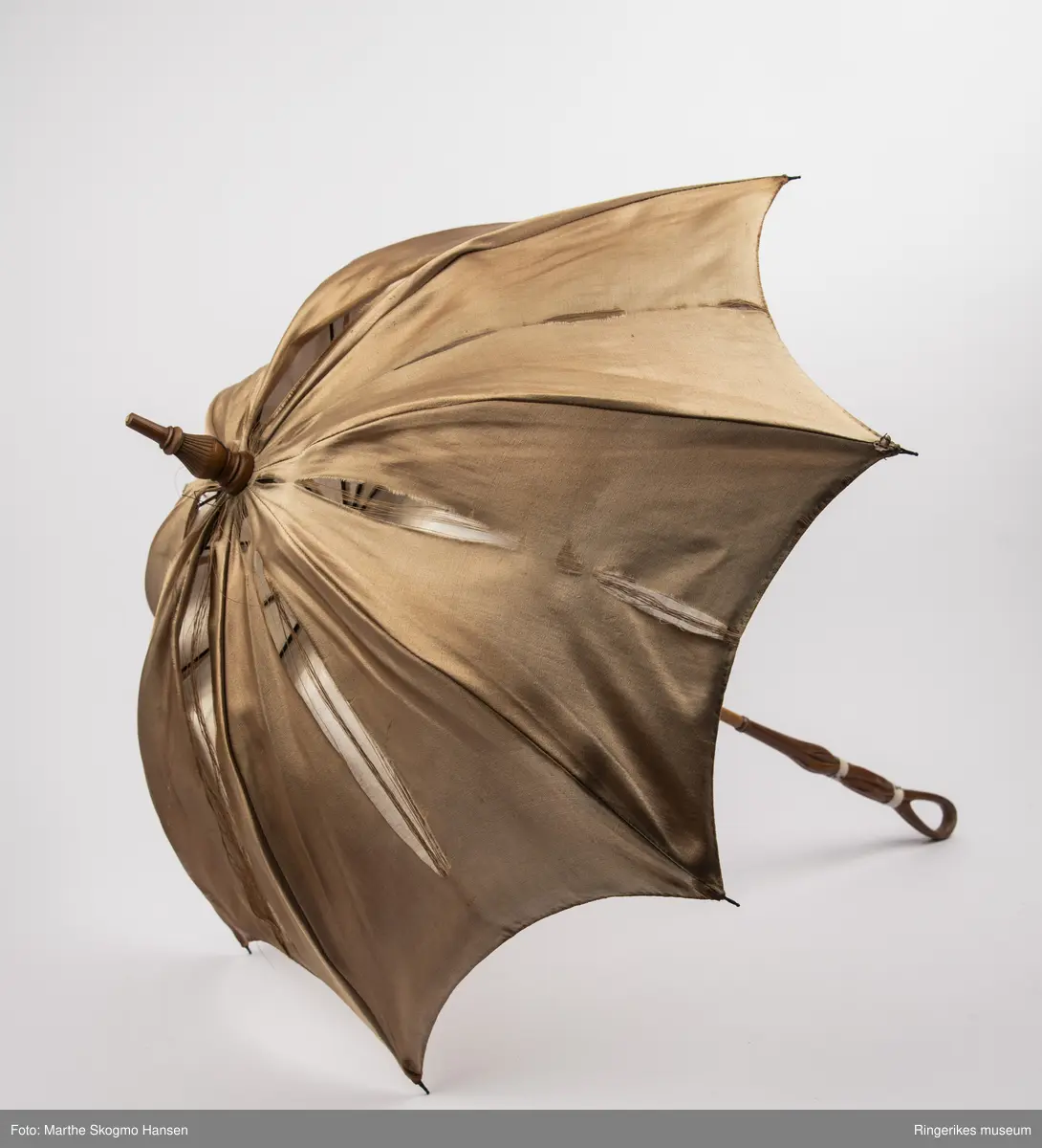 Paraply med dekorert trestang, paraplystoffet er antagelig silke på utsiden og bomull på innsiden.