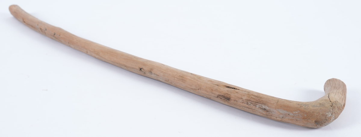 Spaserstokk utskoren av eit stykke einer. Naturvaksen L-form med vinkel til handtak på den eine enden. Stokken har rundt tverrsnitt. Berken var fjerna.