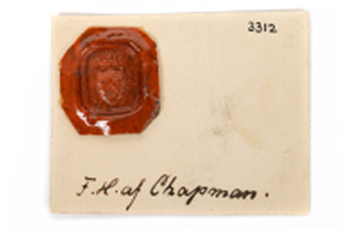 Sigill, guld, med sten av karneol. F.H. af Chapmans adelsvapen. Krönt, hjärtformad sköld med vinkelhake och tre månskäror å räfflad botten. Drivet och ciselerat guld med ring för urkedja. Tillhörande sigilavtryck.