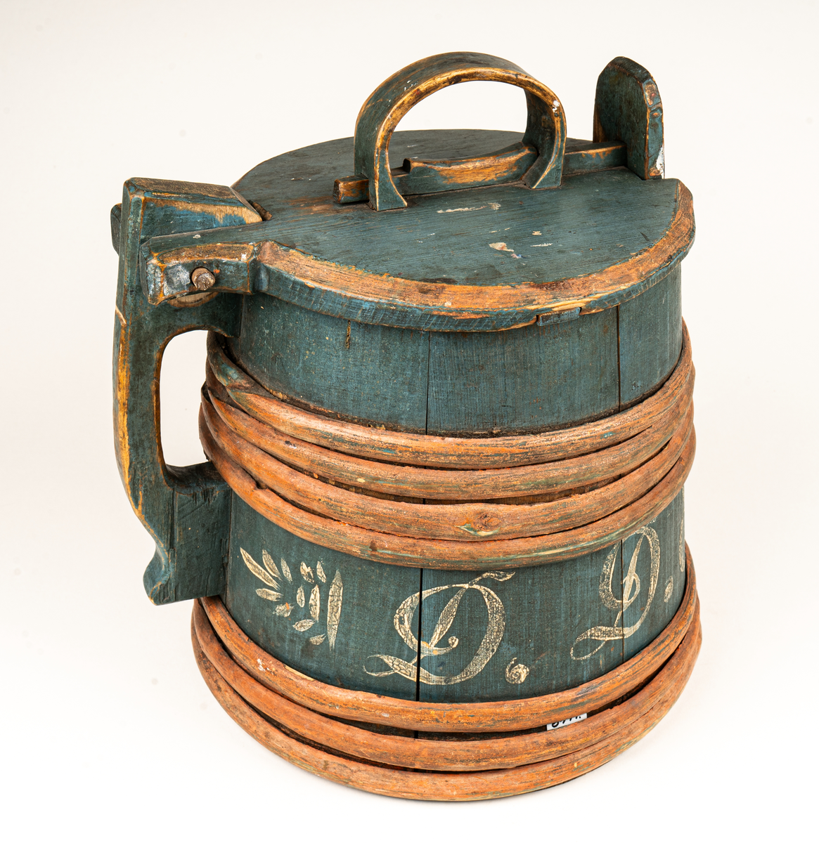 Stånka av trä (furu), laggad, med 7 träband. Målad i grönblått och rött. Märkt DDS år 1853 på sidan med vit färg.