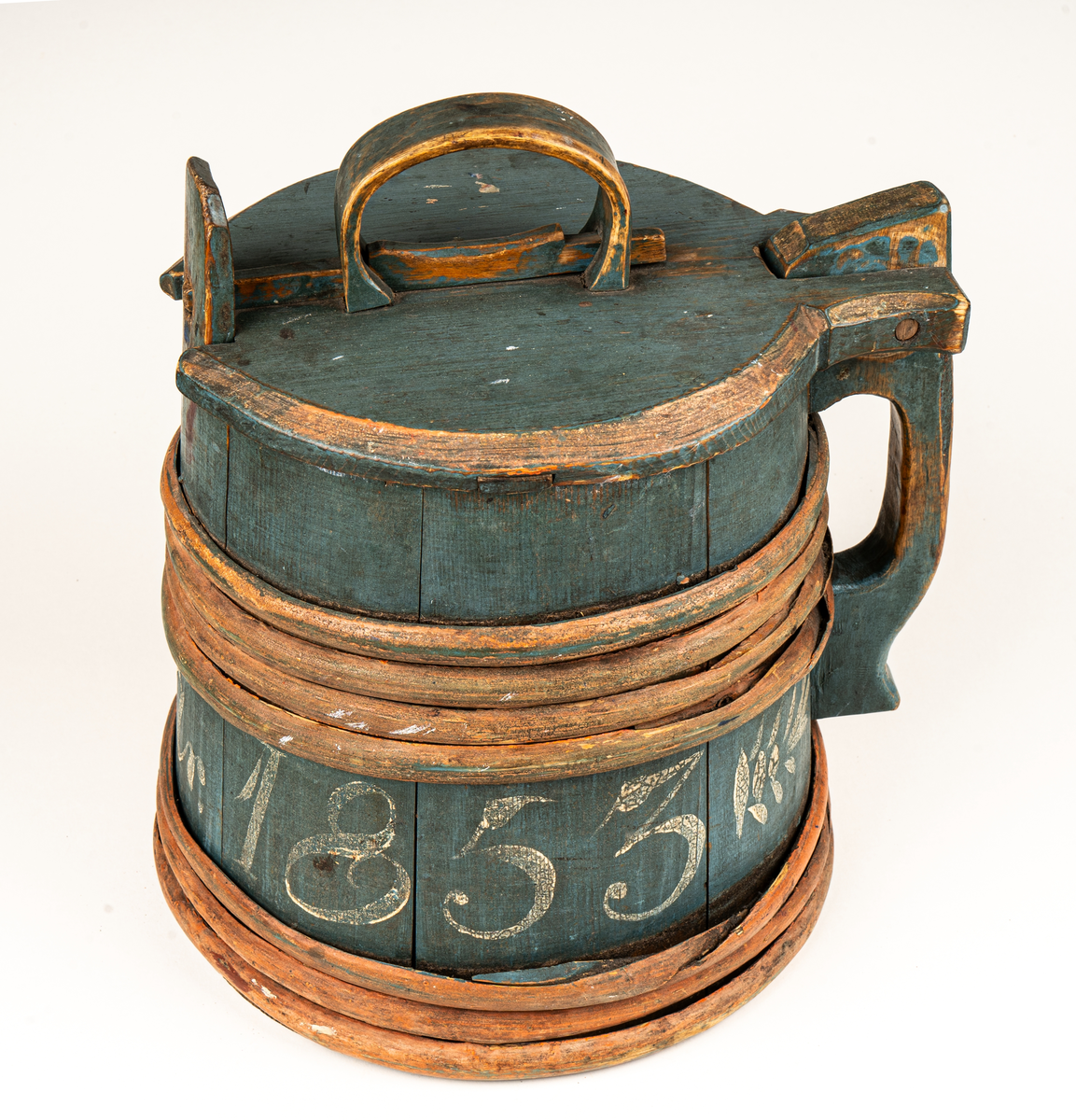 Stånka av trä (furu), laggad, med 7 träband. Målad i grönblått och rött. Märkt DDS år 1853 på sidan med vit färg.